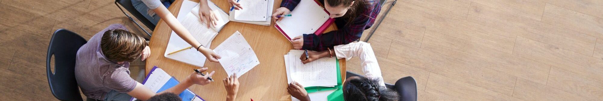 Overhead Shot Of High School Pupils In Group Study Around Tables